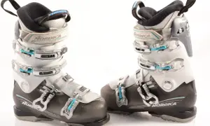 Botas de esquí Nordica para mujer, blancas y negras, con hebillas plateadas y detalles en azul.