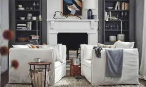 Salón acogedor de Ikea España con sofás blancos, chimenea y estanterías llenas de libros y objetos decorativos.