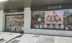 Fachada de tienda Douglas con un anuncio de tres modelos y el lema "one. two. free!".