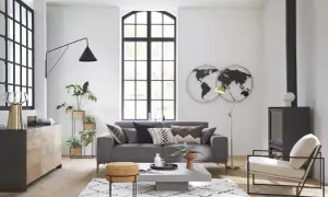 Salón moderno con sofá gris, mesa de centro, chimenea y decoración de mapas del mundo, estilo Maison du Monde.