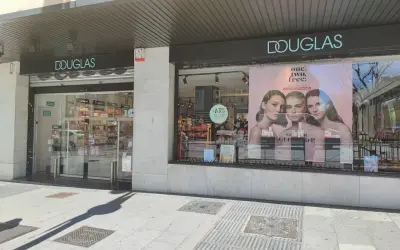 Fachada de tienda Douglas con un anuncio de tres modelos y el lema "one. two. free!".