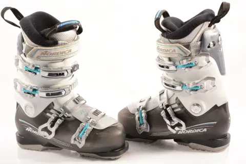 Botas de esquí Nordica para mujer, blancas y negras, con hebillas plateadas y detalles en azul.