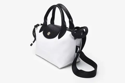 Bolso Longchamp blanco y negro, con asas de cuero y correa ajustable. Ideal para un look moderno y chic.