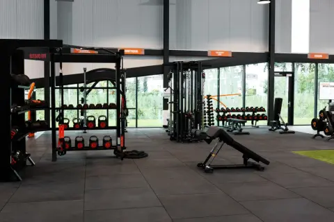 Estanterías con pesas, kettlebells y equipo de entrenamiento funcional en un gimnasio. Todo listo para tu **basic fit**.