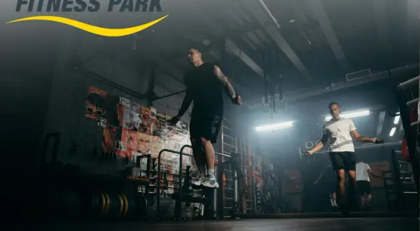 Hombres entrenando en un fitness park, saltando la cuerda en un gimnasio con estilo industrial.