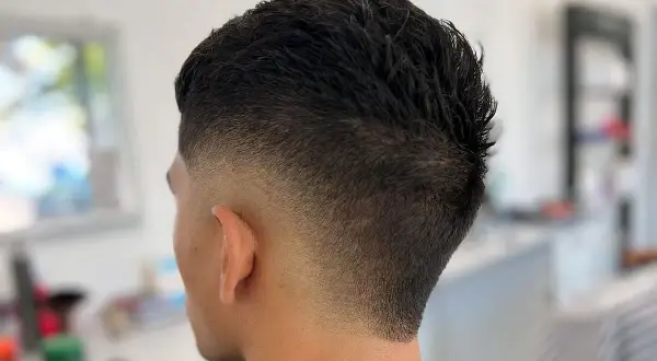 Corte de pelo moderno con un degradado **burst fade** que se desvanece suavemente desde la nuca hacia las orejas.