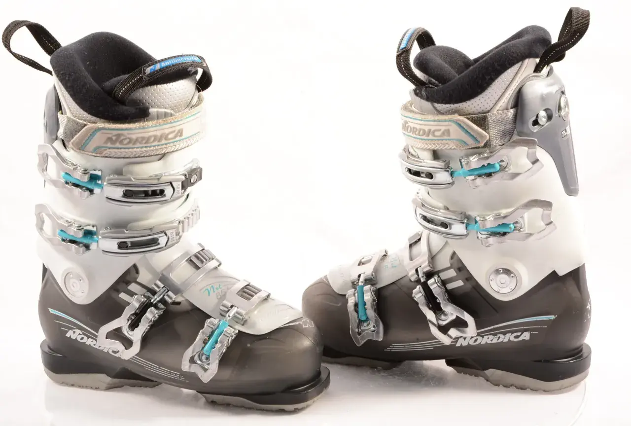 Botas de esquí Nordica para mujer, blancas y negras, con hebillas plateadas y detalles en azul.