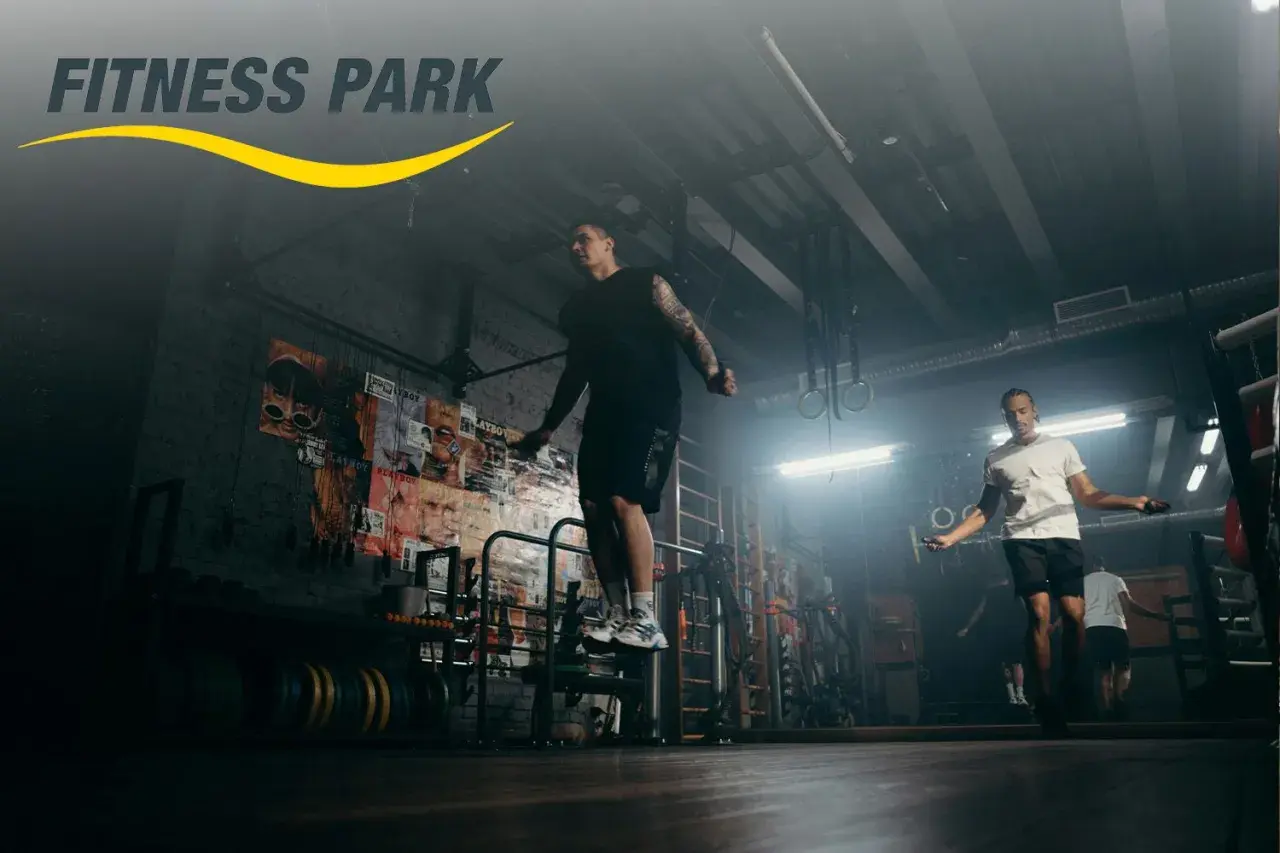 Hombres entrenando en un fitness park, saltando la cuerda en un gimnasio con estilo industrial.