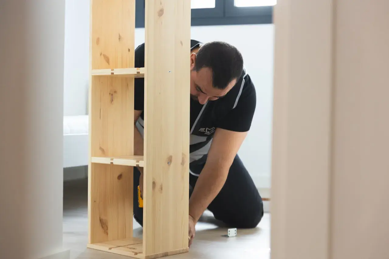 Hombre montando un estante de madera, estilo IKEA.