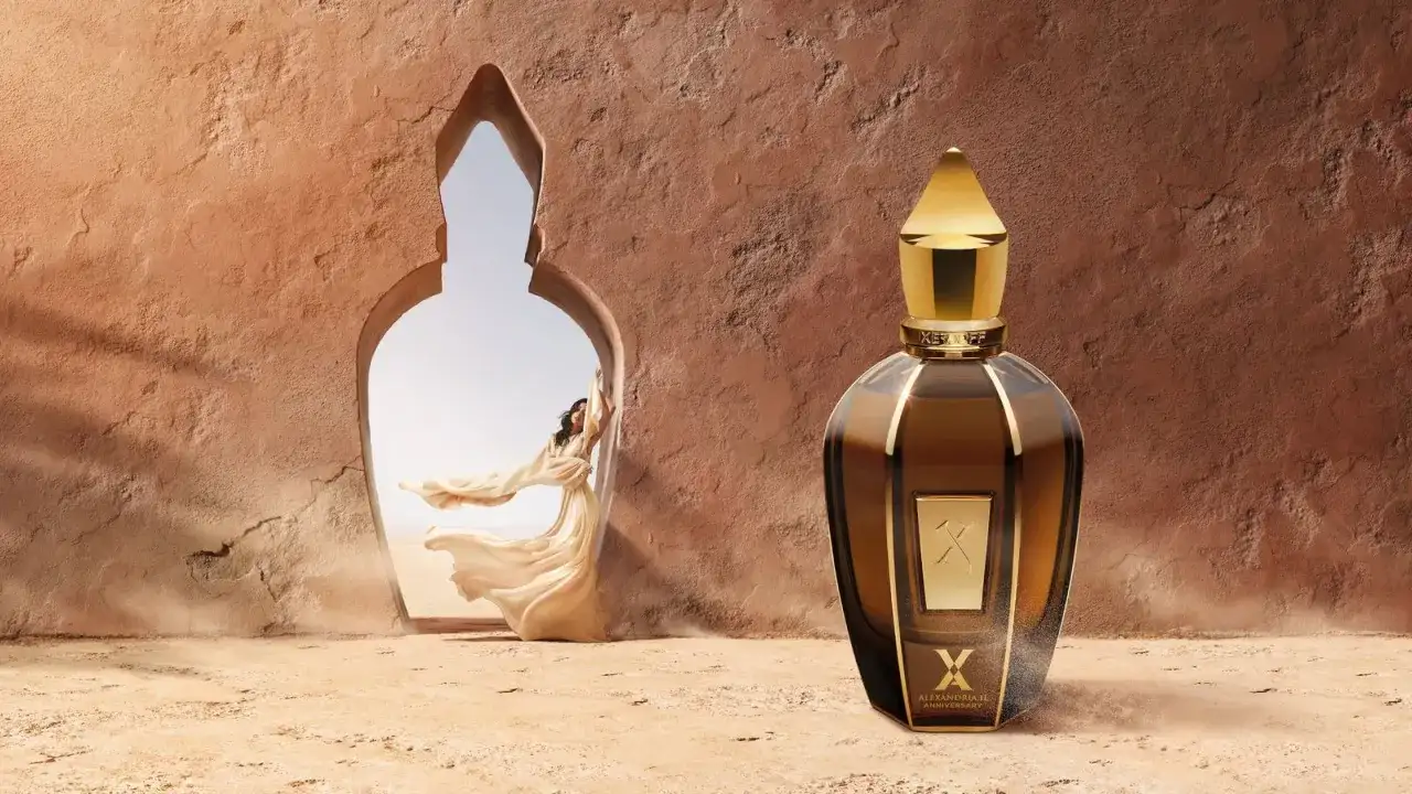 Una mujer con velos flotantes emerge de un arco, evocando la esencia de erba pura. A su lado, un frasco de perfume dorado y ámbar.
