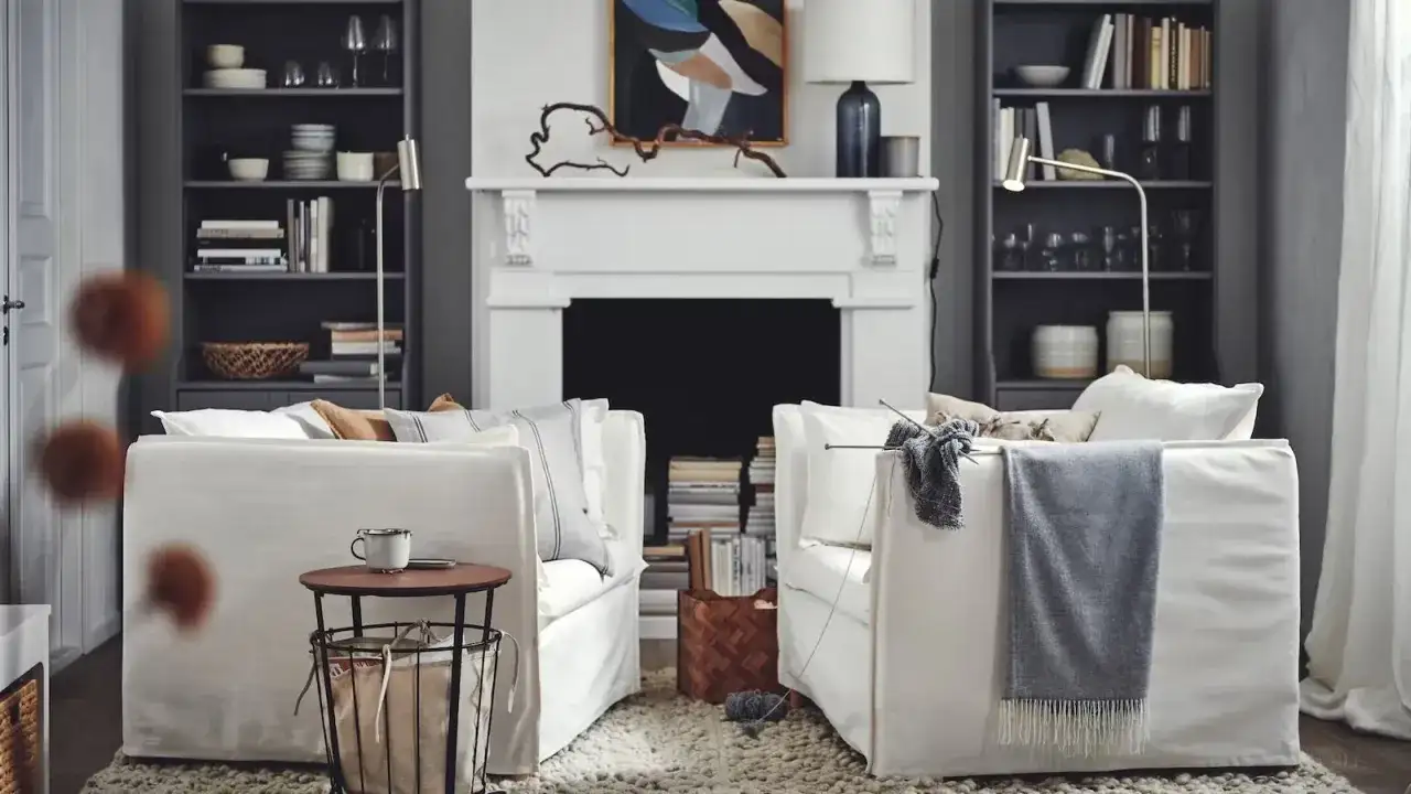 Salón acogedor de Ikea España con sofás blancos, chimenea y estanterías llenas de libros y objetos decorativos.
