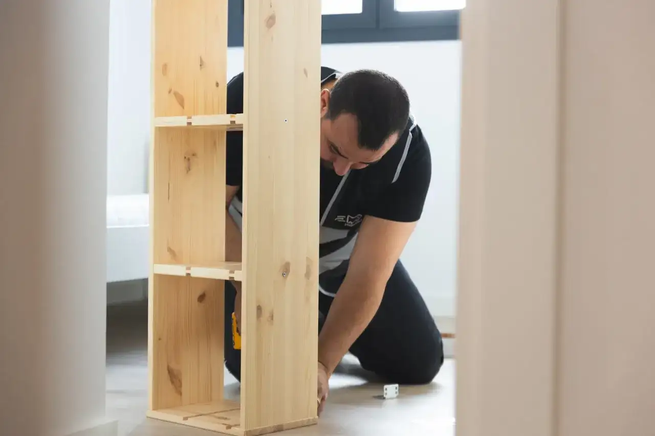 Hombre montando un estante de madera, estilo IKEA.