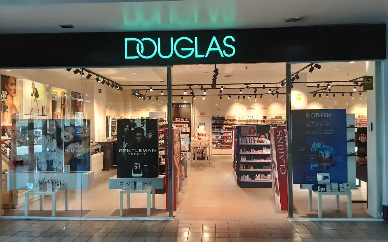 Fachada de tienda Douglas con letrero luminoso y exhibición de productos de belleza y fragancias.