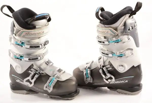 Botas de esquí Nordica para mujer, blancas y negras, con hebillas plateadas y detalles en azul.